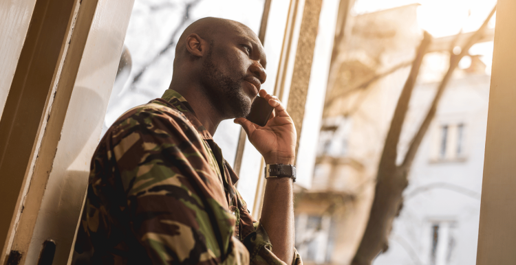 Man looking out at window, listening to phone call.