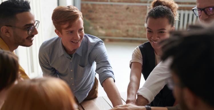 A group of young smiling people huddled together