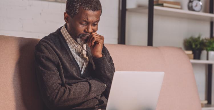 Man looking at laptop while sitting on sofa