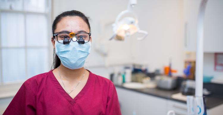 Surgeon wearing a mask in a surgical suite, facing the camera