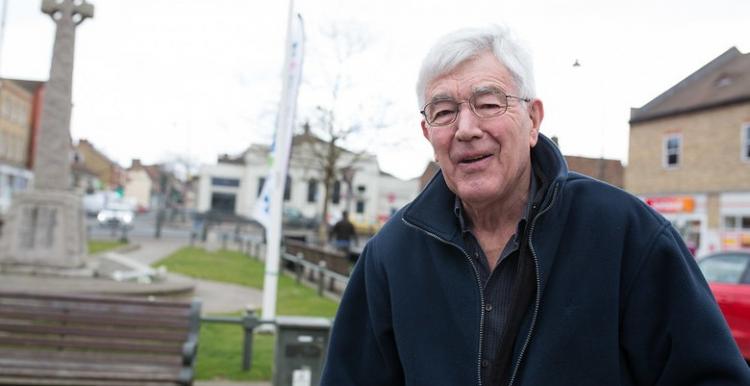 Elderly man with glasses standing outside