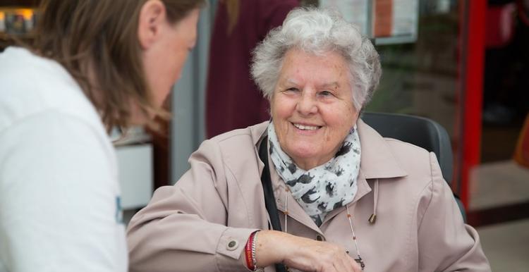 A young lady talking to an older lady sitting in a chair