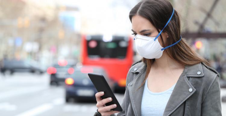 female wearing mask holding phone