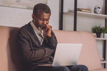 Man looking at laptop while sitting on sofa